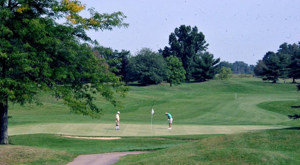 Golfers finish a round on the 18th green at Hawks Nest golf course.