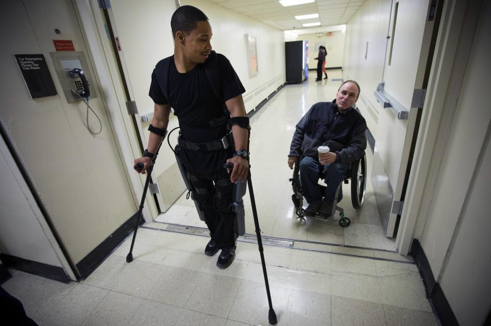 22-year-old Errol Samuels from Queens, New York, who lost the use of his legs in 2012 after a roof collapsed onto him at an off-campus house party near where he was attending college in upstate New York, pauses while walking with a ReWalk electric powered exoskeletal suit to talk to Jim Cesario (R), Spinal Chord Injury Outreach Coordinator, during a therapy session with the ReWalk at the Mount Sinai Medical Center in New York City March 26, 2014. Made by the Israeli company Argo Medical Technologies, ReWalk is a computer controlled device that powers the hips and knees to help those with lower limb disabilities and paralysis to walk upright using crutches. Allan Kozlowski, assistant professor of Rehabilitation Medicine at Icahn School of Medicine at Mount Sinai hospital, where patients like Samuels are enrolled in his clinical trials of the ReWalk and another exoskeleton, the Ekso (Ekso Bionics) hopes machines like these will soon offer victims of paralysis new hope for a dramatically improved quality of life and mobility. The ReWalk is currently only approved by the U.S. Food and Drug Administration (FDA) for use in rehabilitation facilities like at Mount Sinai, as they weigh weather to approve the device for home use as it already is in Europe. Picture taken March 26, 2014. REUTERS/Mike Segar