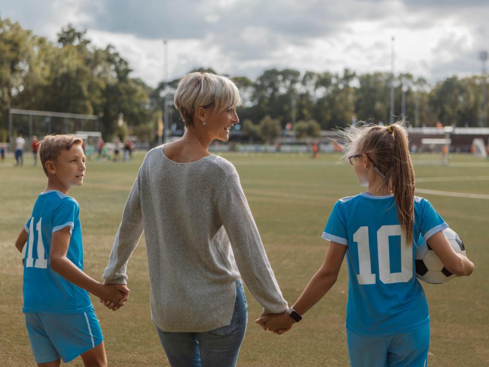 Female Soccer mom football coach with two children during a training session