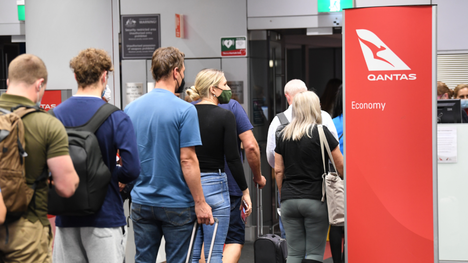 Qantas passengers line up at an airport gate to board a flight.