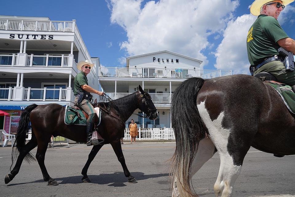 Joe and John Galvin of the Hampton Police Department Mounted Patrol ride their horses along Ocean Boulevard on hot summer Monday, August 10, 2020, at Hampton Beach.