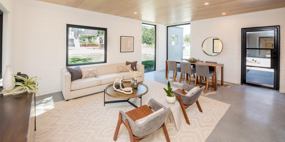 a living room with communal seating, a small table, and windows