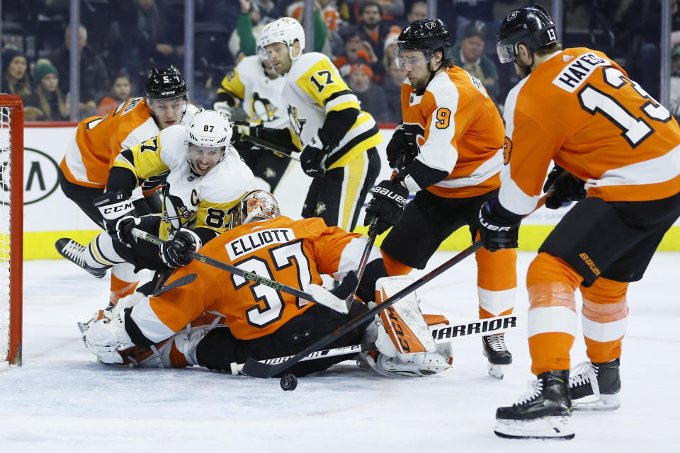 Pittsburgh Penguins' Sidney Crosby (87) tries to get a shot past Philadelphia Flyers' Brian Elliott (37) as Philippe Myers (5), Ivan Provorov (9) and Kevin Hayes (13) defend during the third period of an NHL hockey game, Tuesday, Jan. 21, 2020, in Philadelphia. (AP Photo/Matt Slocum)