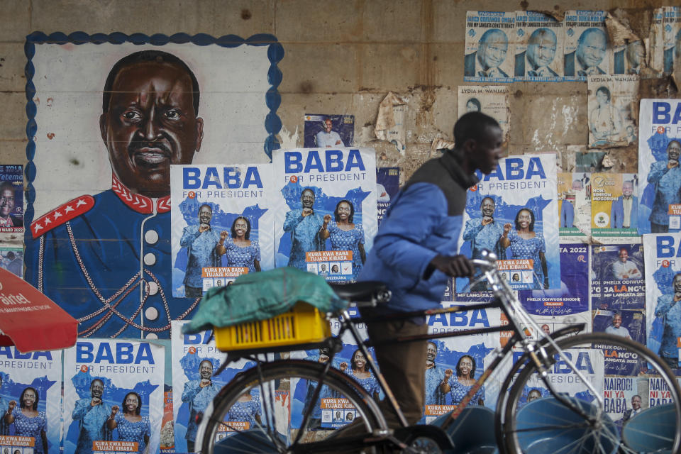 A man pushes a bicycle past campaign posters for Kenyan presidential candidate Raila Odinga, referred to affectionately as "Baba", the Swahili word for "father", and his running mate Martha Karua, in the low-income Kibera neighborhood of Nairobi, Kenya Friday, July 29, 2022. Kenya's Aug. 9 election is ripping open the scars of inequality and corruption as East Africa's economic hub chooses a successor to President Uhuru Kenyatta. (AP Photo/Brian Inganga)