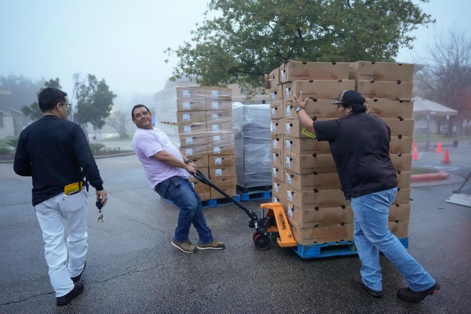 Volunteer Tony Cruz, center, and H-E-B truck driver Pedro Ramos, right, unload a truck full of groceries for an annual holiday dinner giveaway at El Buen Samaritano on Friday. "It’s really a time where magic happens at El Buen,” said Georgia Hernandez, the mission’s donor relations manager.