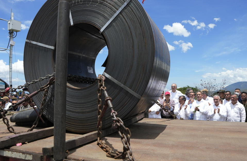 A roll of iron sits on the back of a cargo truck that crosses the Simon Bolivar International Bridge from Venezuela to Colombia during a ceremony marking the border's reopening to cargo trucks, between Cucuta, Colombia and San Antonio del Tachira, Venezuela, Monday, Sept. 26, 2022. Behind are Colombia's President Gustavo Petro and Venezuela's Transportation Minister Ramon Araguayan. (AP Photo/Fernando Vergara)