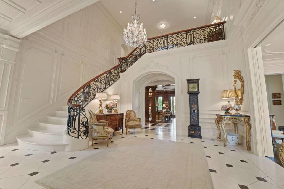 The home, located at 7330 Baltusrol Lane, includes a marble foyer and curved staircase beneath 14-foot ceilings, according to its listing.
