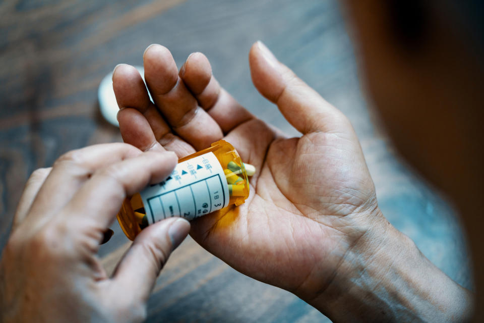 A person taking pills out of a container