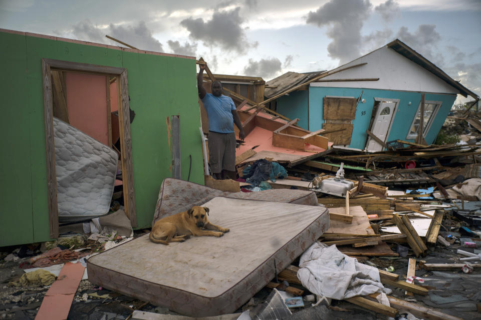 A man stands next to a destroyed house as a dog named Francoise rests on a mattress in the rubble left by Hurricane Dorian in Abaco, Bahamas, Monday, Sept. 16, 2019. Dorian hit the northern Bahamas on Sept. 1, with sustained winds of 185 mph (295 kph), unleashing flooding that reached up to 25 feet (8 meters) in some areas. (AP Photo/Ramon Espinosa)