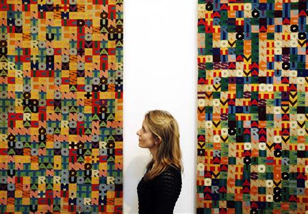 A Christie's employee poses with Alighiero Boetti's artworks "Addizione" (L) and "Sottrazione" at Christie's Mayfair gallery in London February 5, 2014. REUTERS/Luke MacGregor