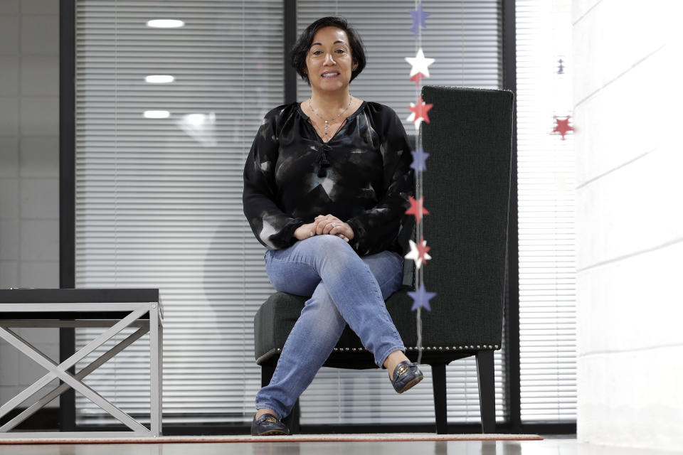 In this March 25, 2020, photo, Attorney Margarita Silva sits in her office in Phoenix. Silva was recently denied entry to a hearing inside an immigration detention center under a new requirement for lawyers to bring their own masks, protective eye gear and gloves to protect against coronavirus. While some immigration courts have closed, the Trump administration has insisted on keeping many open amid fierce resistance from judges and even Homeland Security Department attorneys. (AP Photo/Matt York)