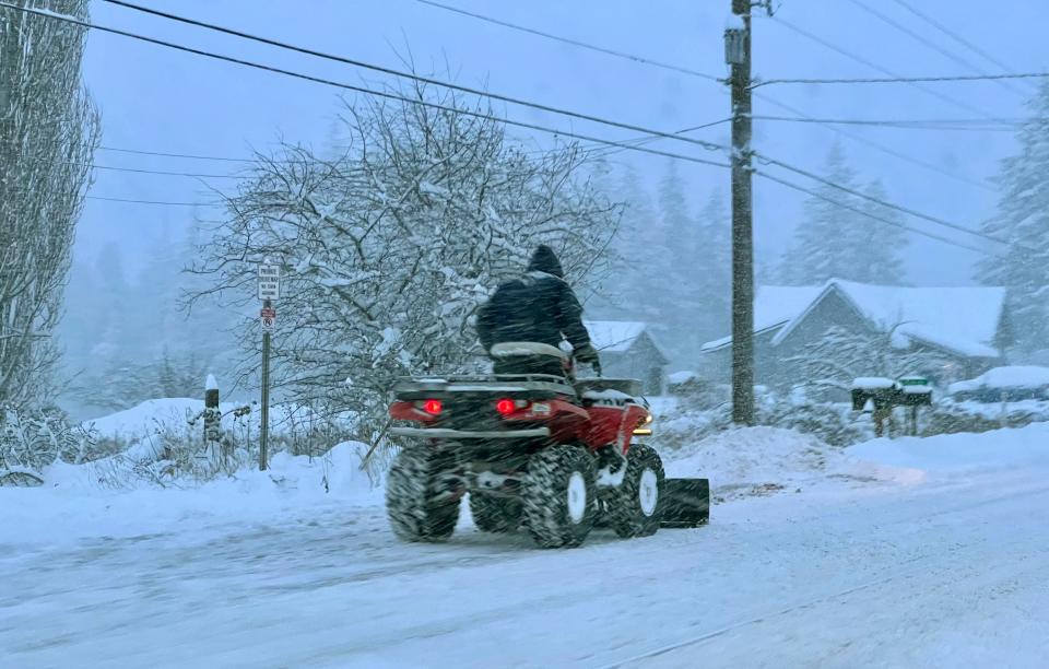 A four-wheeler plowS snow northeast of Bellingham, Wash., on Dec. 20, 2022. Heavy snow, freezing rain and sleet have disrupted travel across the Pacific Northwest, causing widespread flight cancellations and creating hazardous driving conditions.