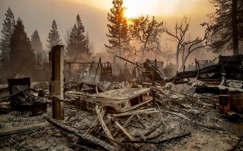 A vintage car rests among debris as the Camp Fire tears through Paradise - Credit:  Noah Berger/AP