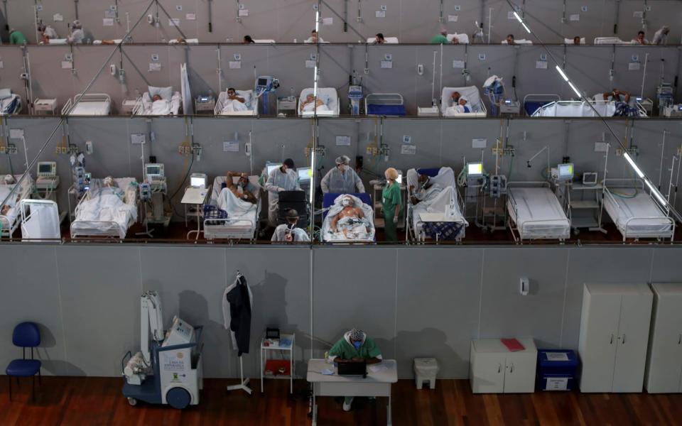 Healthcare workers treat a patient among others suffering from the coronavirus at a field hospital set up at Dell'Antonia sports gym in Santo Andre - Reuters