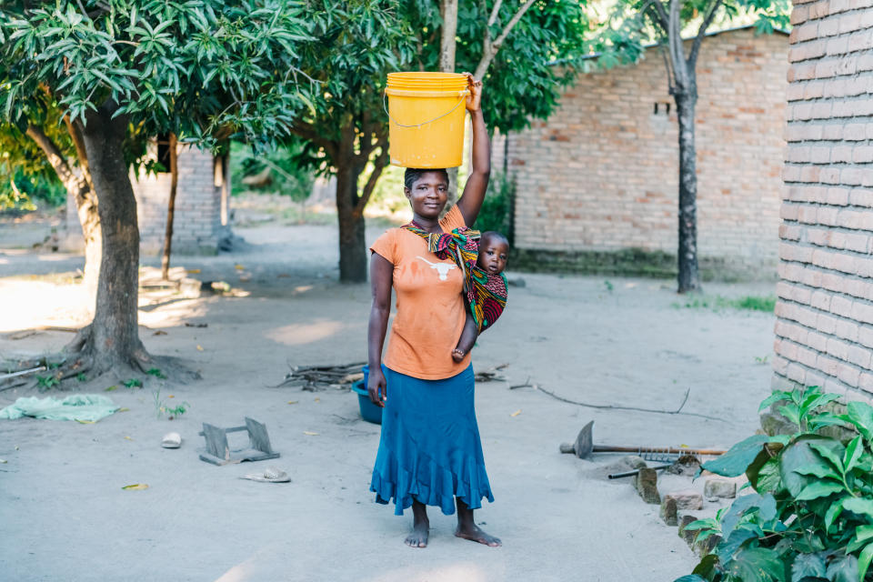 Una madre carga a su hijo y un bote de agua en una aldea de Malaui. (Getty Images)