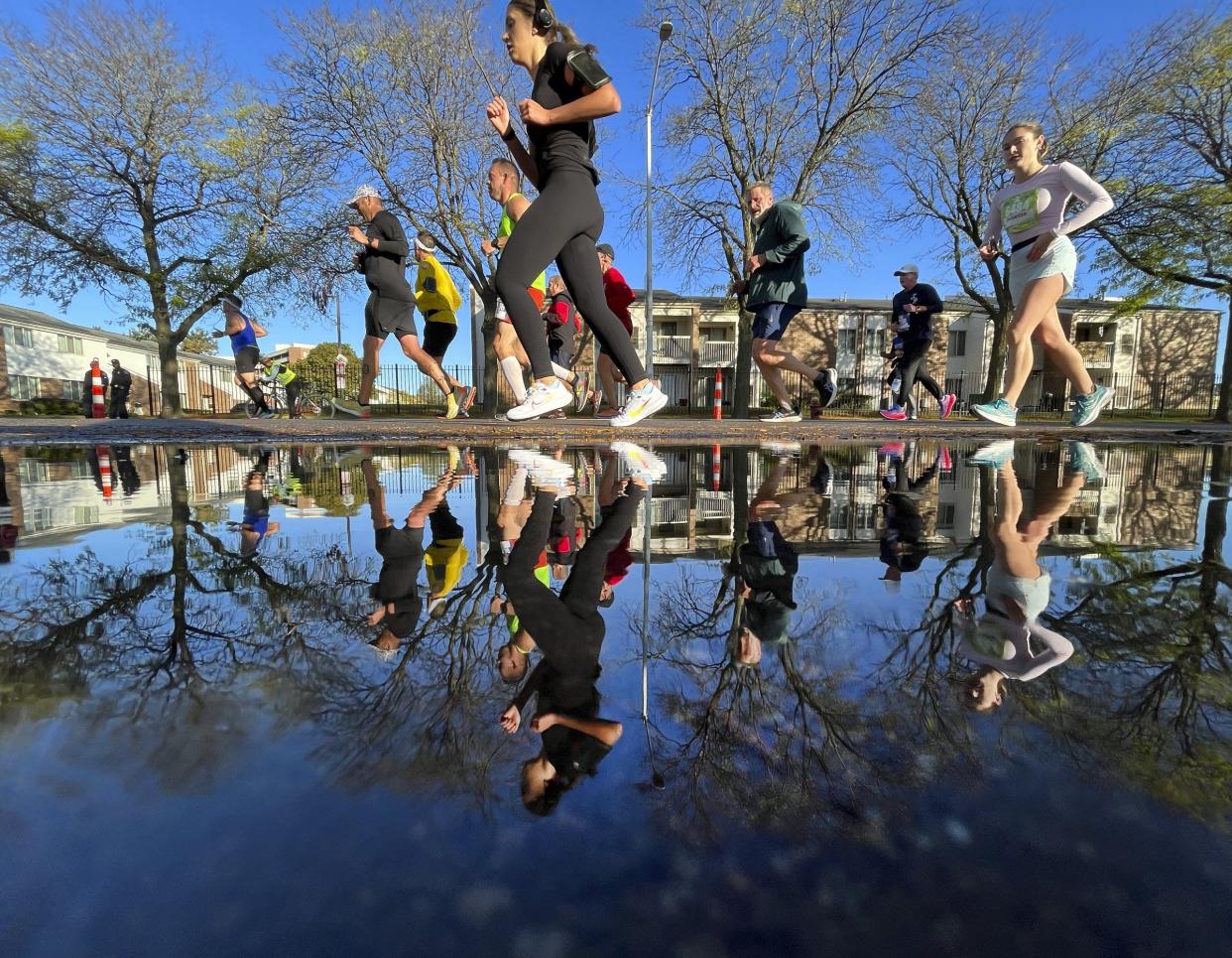 Runners are reflected in a puddle on Forest during the 46th Annual Detroit Free Press Marathon presented by MSU Federal Credit Union in Detroit on Oct. 15, 2023.