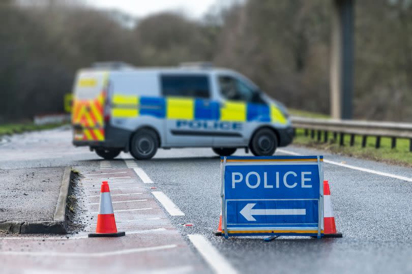 A police road closed sign with a police car in the background