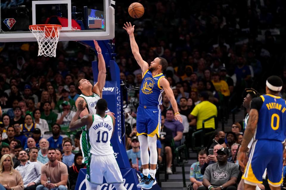 Dallas Mavericks' Dorian Finney-Smith (10) and Dwight Powell, left rear, defend against a shot by Golden State Warriors guard Stephen Curry (30) in the first half of an NBA basketball game in Dallas, Thursday, March, 3, 2022. (AP Photo/Tony Gutierrez)