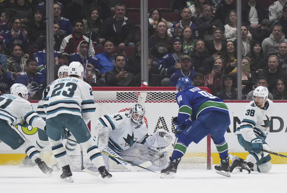 Vancouver Canucks' Andrei Kuzmenko (96) scores against San Jose Sharks goalie James Reimer (47) during the first period of an NHL hockey game in Vancouver, British Columbia, Thursday, March 23, 2023. (Darryl Dyck/The Canadian Press via AP)