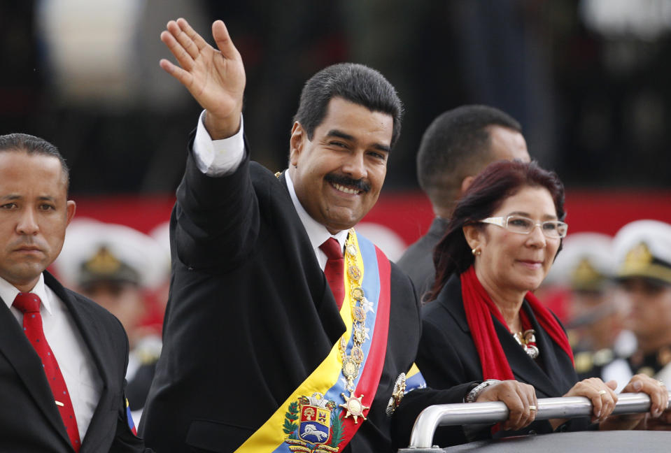 ARCHIVO - El presidente de Venezuela, Nicolás Maduro, saluda desde un vehículo junto a su compañera Cilia Flores en una ceremonia militar en su honor como comandante en jefe, en Caracas, Venezuela, el 19 de abril de 2013. (AP Foto/Ariana Cubillos, Archivo)