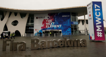 Workers walk past the main entrance of the Mobile World Congress in Barcelona, Spain February 24, 2017. REUTERS/Albert Gea