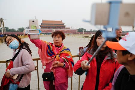 People take pictures of themselves as they attend a flag-raising ceremony at Tiananmen Square a day before the 19th National Congress of the Communist Party of China begins in Beijing, China, October 17, 2017. REUTERS/Damir Sagolj