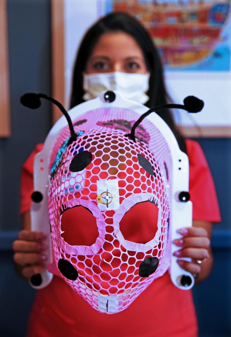 Radiation therapist Courtney Shanmugabaskaran holds up the Pink Lady mask that she painted for a child undergoing radiation therapy. Shanmugabaskaran paints masks for pediatric patients at the Cancer Center at Children’s Wisconsin; Froedtert & MCW. She has painted close to 40 that include a variety of themes.  Angela Peterson/Milwaukee Journal Sentinel