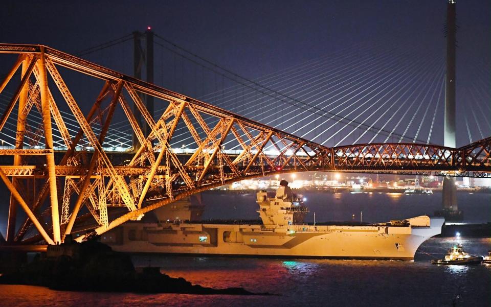 HMS Queen Elizabeth, is pulled by tug boats underneath the Forth Rail Bridge as departs for sea trials in the North Sea on June 26, 2017  -  Jeff J Mitchell