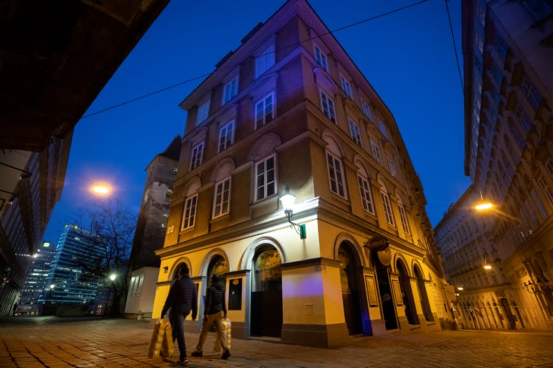 People carry toilet paper as they walk past closed bars of nightlife area "Bermuda Triangle" during the coronavirus disease (COVID-19) outbreak in Vienna