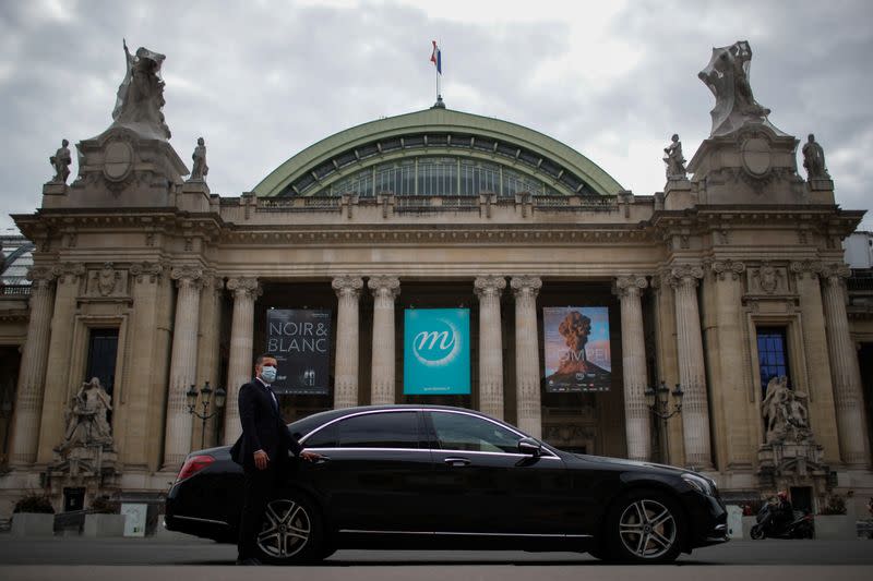 A chauffeur poses next to a Mercedes-Benz luxury car of Chabe, Chauffeured Cars Services, in front of the Grand Palais in Paris