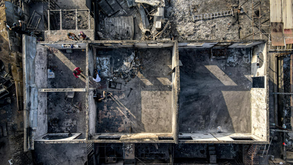 People clean up what is left amid the rubble of homes burned by a deadly forest fire in Vina del Mar, Chile, Monday, Feb. 5, 2024. (AP Photo/Esteban Felix)