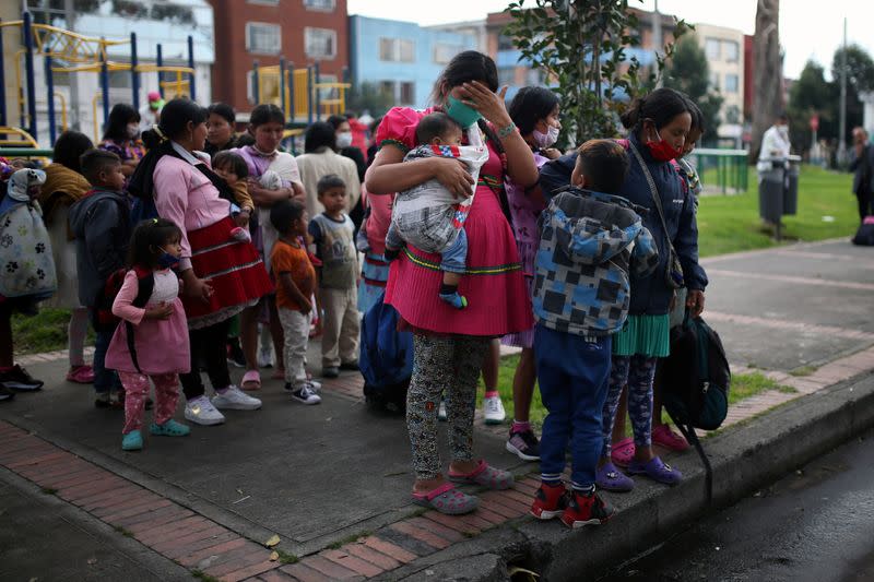 Indigenous people wearing protective face masks as a preventive measure against the spread of the coronavirus disease (COVID-19) carry their belongings after being evicted from a building in Bogota