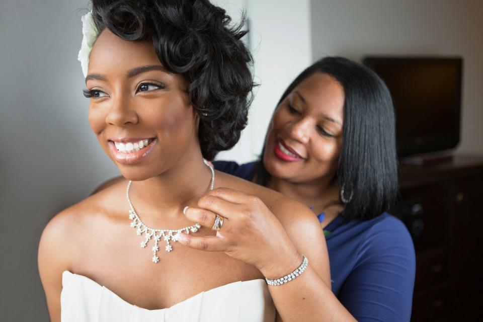 A mother putting a necklace on a bride.