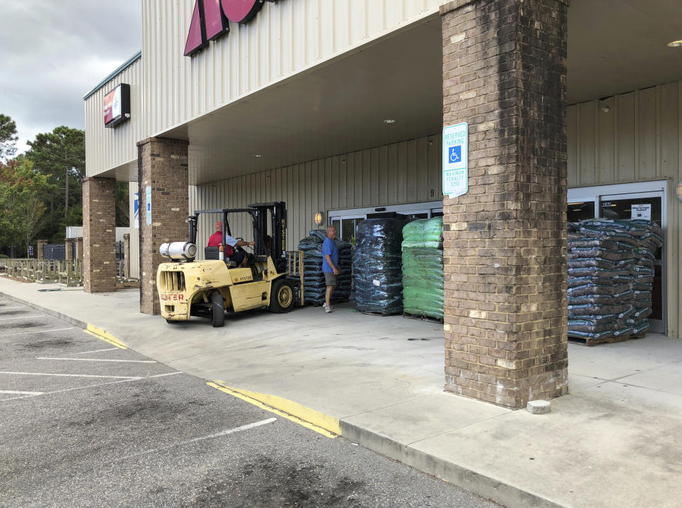 In this Wednesday, Sept. 12, 2018 photo, Manager Tom Roberts watches as an employee positions a pallet of mulch to protect the Ace Hardware store from Hurricane Florence in Calabash, N.C. Roberts still had supplies like bottled water, but went ahead and closed so his employees could prepare their homes. (AP Photo/Jeffrey Collins)