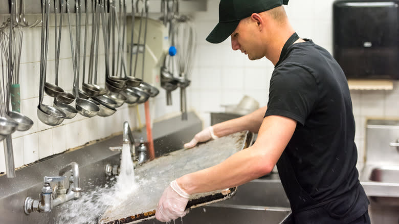 fast food employee washing dishes 