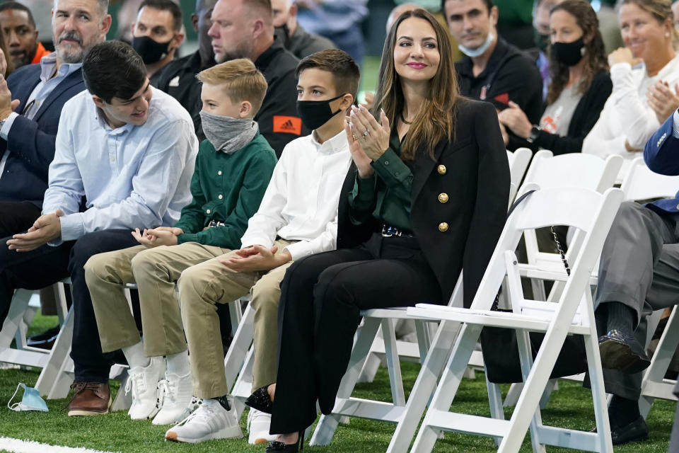 Jessica Cristobal, right, applauds as her husband, Miami football coach Mario Cristobal, is introduced at a news conference Tuesday, Dec. 7, 2021, in Coral Gables, Fla. Cristobal is returning to his alma mater, where he won two championships as a player. Jessica is seated with their two sons, Rocco Cristobal, 10, second from left, and Mario Mateo, 11, second from right. (AP Photo/Lynne Sladky)