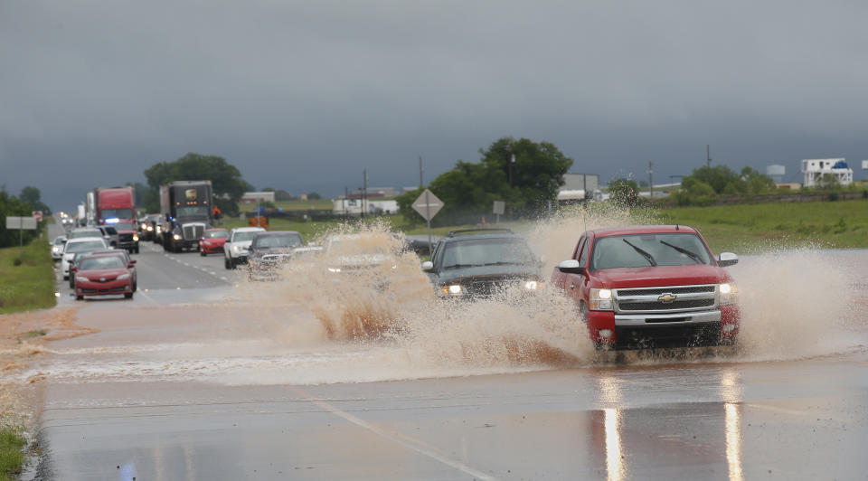 Unos carros pasan por una parte de la carretera federal 66 con agua empozada, tras fuertes lluvias el martes 21 de mayo del 2019, en El Reno, Oklahoma. (AP Foto/Sue Ogrocki)