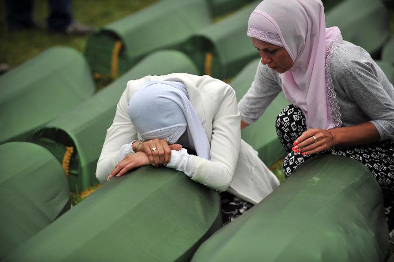 A Bosnian Muslim woman, survivor of the Srebrenica 1995 massacre cries by the coffin of a relative, layed out among others at the memorial cemetery in the village of Potocari near the eastern-Bosnian town of Srebrenica, on July 11, 2014