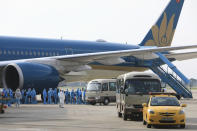 Vietnamese COVID-19 patients in protective gear arrive at the Noi Bai airport in Hanoi, Vietnam on Wednesday, July 29, 2020. The 129 patients who were working in Equatorial Guinea are brought home in a repatriation flight for treatment of the coronavirus. (Tran Huy Hung/VNA via AP)