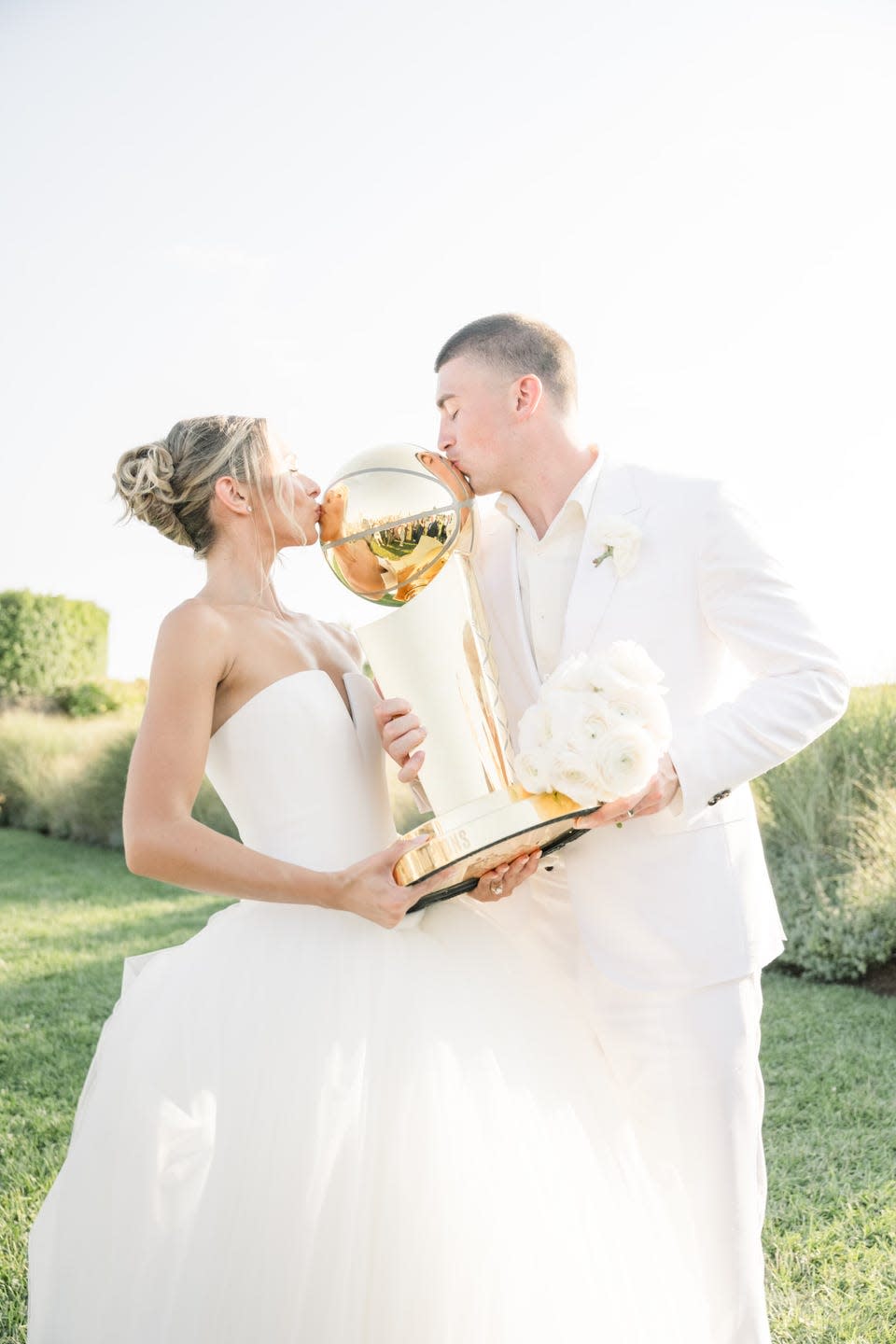 a couple kisses an NBA trophy