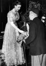 <p>Princess Margaret, wearing a lace dress and long gloves, receives a flower bouquet in 1949.</p>