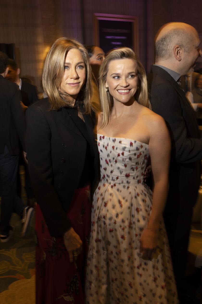 A woman in black next to a woman in a light patterned dress.