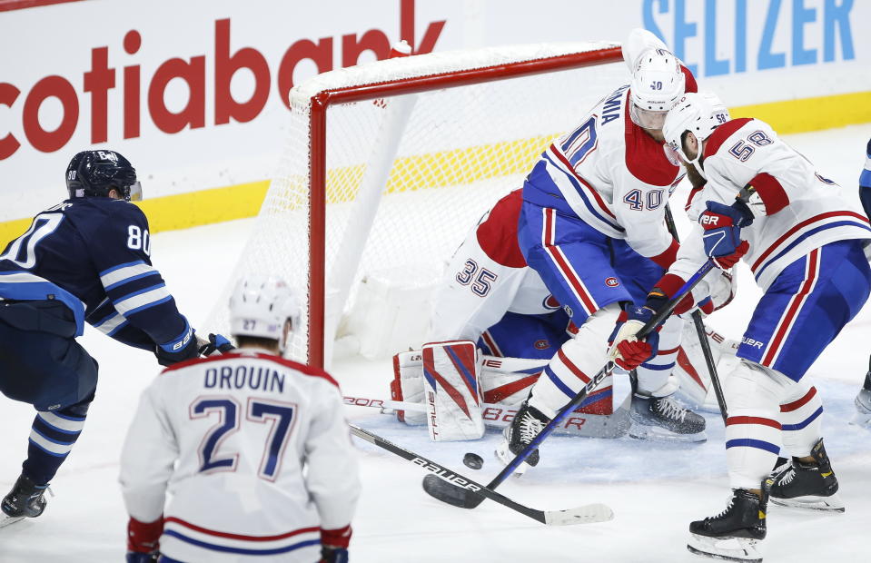 Montreal Canadiens' David Savard (58) tries to clear the puck as Joel Armia (40) defends in front of goaltender Sam Montembeault (35) as Winnipeg Jets' Pierre-Luc Dubois (80) tries to tap in the rebound during third-period NHL hockey game action in Winnipeg, Manitoba, Thursday, Nov. 3, 2022. (John Woods/The Canadian Press via AP)