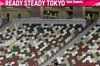 A support team member is seen in almost deserted spectators seats during an athletics test event for Tokyo 2020 Olympic Games at the National Stadium in Tokyo Sunday, May 9, 2021. The pressure of hosting an Olympics during a still-active pandemic is beginning to show in Japan. The games begin July 23, with organizers determined they will go on, even with a reduced number of spectators or possibly none at all.(AP Photo/Shuji Kajiyama)