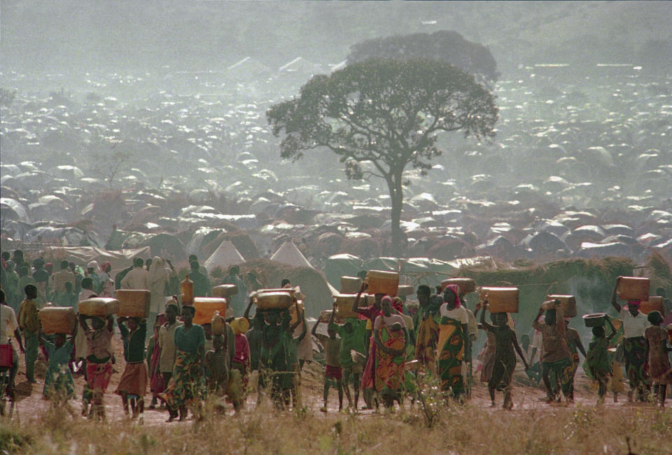 FILE - Refugees who fled the ethnic bloodbath in neighboring Rwanda carry water containers back to their huts at the Benaco refugee camp in Tanzania, near the border with Rwanda, May 17, 1994. (AP Photo/Karsten Thielker, File)