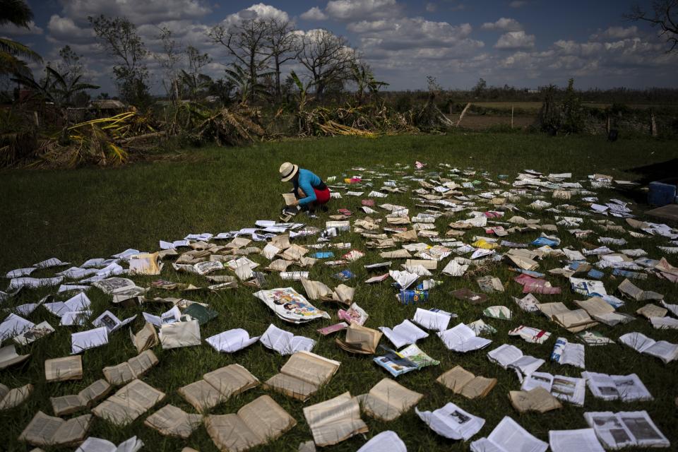 A teacher dries out books at a school that was heavily damaged by Hurricane Ian in La Coloma, in the province of Pinar del Rio, Cuba, on Oct. 5, 2022. (AP Photo/Ramon Espinosa)