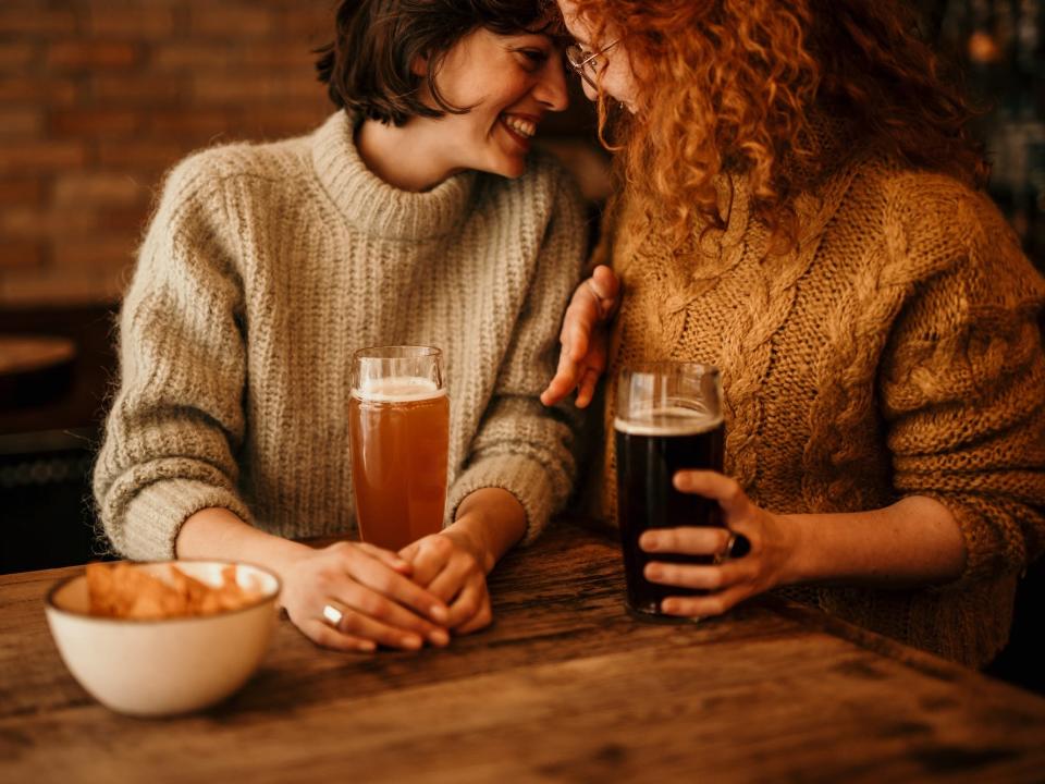 Two women lean together at a brewery.