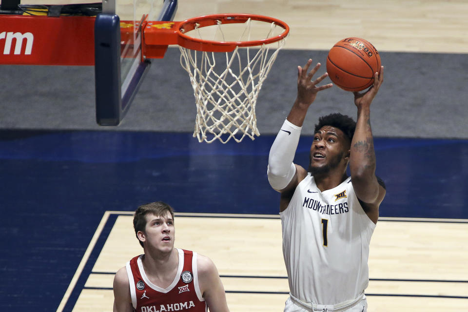 West Virginia forward Derek Culver (1) shoots while defended by Oklahoma guard Austin Reaves (12) looks on during the first half of an NCAA college basketball game Saturday, Feb. 13, 2021, in Morgantown, W.Va. (AP Photo/Kathleen Batten)