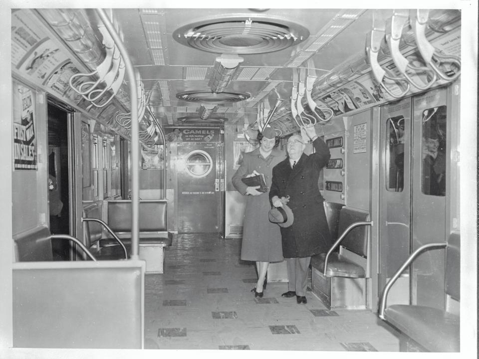 Two people stand next to each other in an otherwise empty subway cart