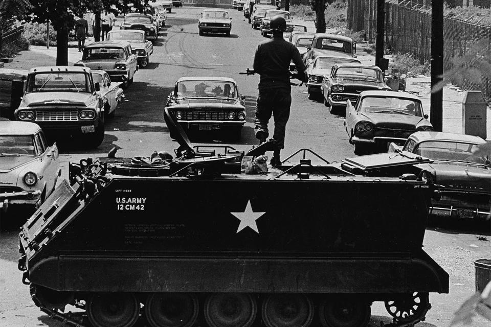 <p>Don Hogan Charles took this image for the <em>New York Times</em> of a National Guardsmen standing with a rifle atop a personnel carrier vehicle, blocking traffic from leaving the area during race riots in Newark, New Jersey on July 16, 1967.</p>